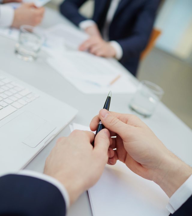 Image of human hands with pen during work planning at meeting